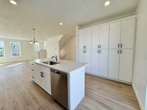 Kitchen featuring white cabinetry, pendant lighting, stainless steel dishwasher, recessed lighting, and light wood finished floors