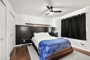 Bedroom with wood finished floors, two closets, and ceiling fan