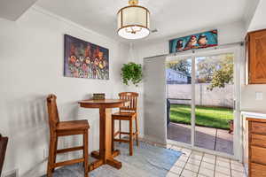 Dining space with light tile patterned flooring, ornamental molding, and a textured ceiling