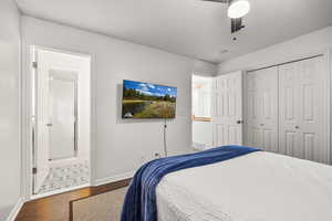 Bedroom with wood finished floors, a closet, a ceiling fan, and ensuite bathroom