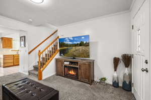 Living room with light colored carpet, a lit fireplace, stairway, and a textured ceiling
