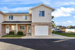 Traditional home featuring a porch, brick siding, a garage, and driveway