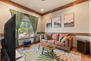 Living area with wood finished floors, crown molding, and recessed lighting