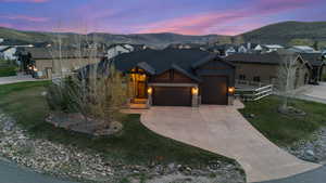 View of front of home featuring an attached garage, stone siding, driveway, and a mountain view