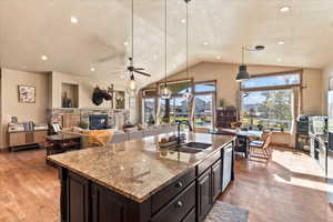 Kitchen featuring a ceiling fan, light stone countertops, vaulted ceiling, decorative light fixtures, and a textured ceiling