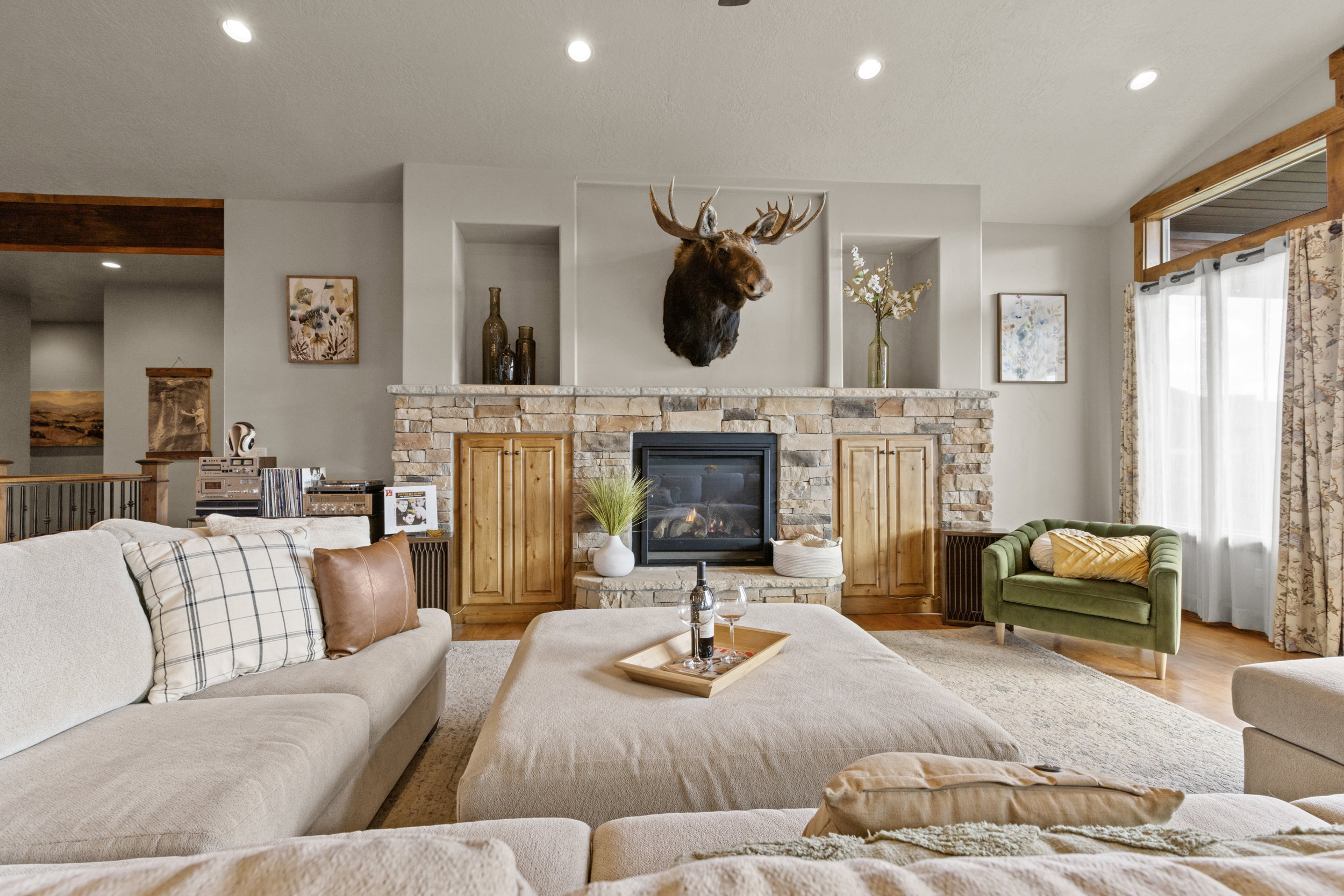 Living room with recessed lighting, wood finished floors, and a stone fireplace