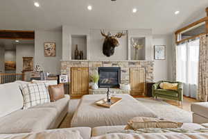 Living room with recessed lighting, wood finished floors, and a stone fireplace
