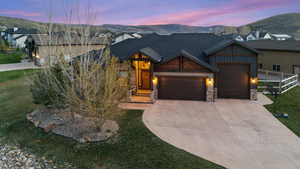 View of front of property with a garage, stone siding, driveway, and a mountain view