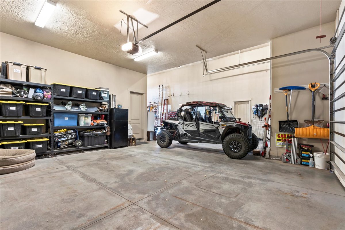 Garage with a garage door opener, two cars fit with the side-by-side between the RV bay and car bay.