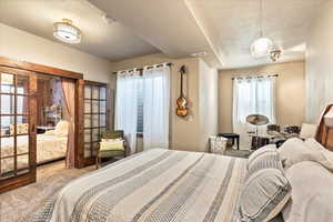 Carpeted bedroom with a textured ceiling and french doors