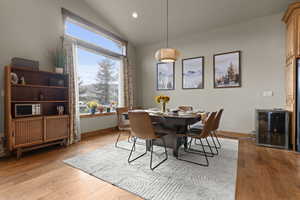 Dining area featuring wine cooler, lofted ceiling, light wood finished floors, and recessed lighting