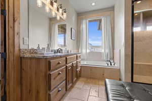 Primary ensuite; Full bathroom featuring stone tile flooring, vanity, a garden tub, a shower stall, and recessed lighting