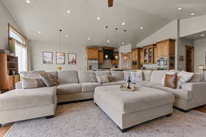 Living area with lofted ceiling, light wood-style flooring, recessed lighting, and ceiling fan