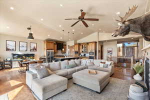 Living room featuring light wood-type flooring, a fireplace, ceiling fan, recessed lighting, and high vaulted ceiling