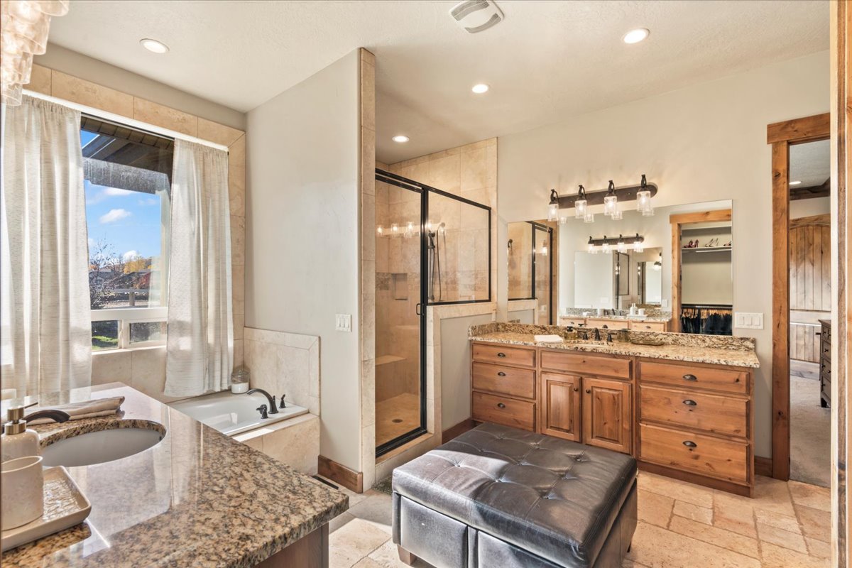Primary ensuite; Bathroom with two vanities, a garden tub, a shower stall, recessed lighting, and stone tile floors