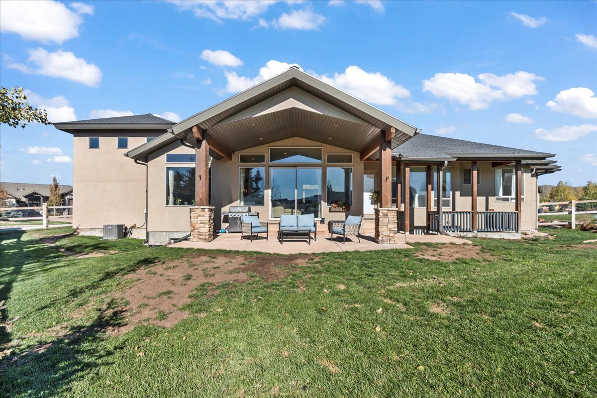 Rear view of property featuring stucco siding, a patio area, outdoor lounge area, and stone siding