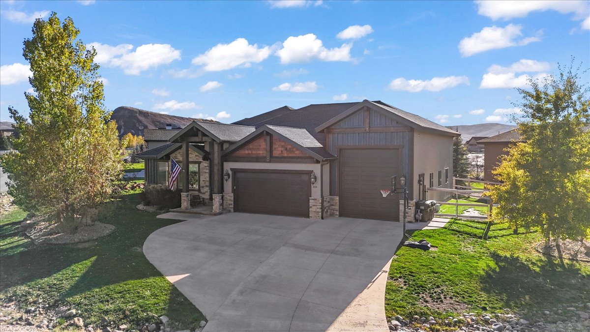 Craftsman house featuring an attached garage, stone siding, driveway, and a front yard