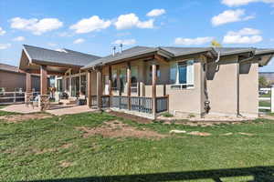 Rear view of house with stucco siding, a patio area, and a shingled roof
