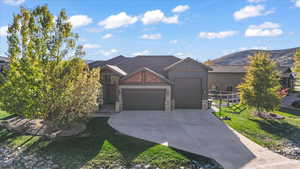 View of front facade with stone siding, a garage, driveway, a mountain view, and board and batten siding