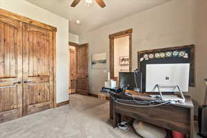Carpeted office featuring ceiling fan and baseboards