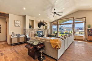 Living room featuring a textured ceiling, lofted ceiling, wood finished floors, a fireplace, and recessed lighting