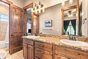 Ensuite bathroom featuring double vanity, ceiling fan, and shower / bath combo with shower curtain