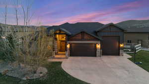 Craftsman-style house featuring an attached garage, stone siding, driveway, and a mountain view
