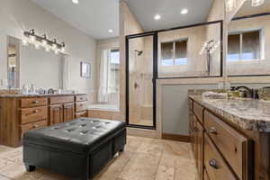 Primary ensuite. Full bathroom featuring two vanities, a garden tub, stone tile flooring, a shower stall, and recessed lighting