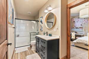 Full bath with vanity, a stall shower, and light wood-type flooring