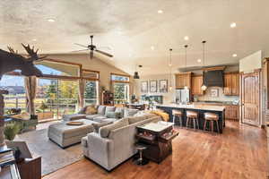 Living area featuring a textured ceiling, light wood-type flooring, lofted ceiling, a ceiling fan, and recessed lighting