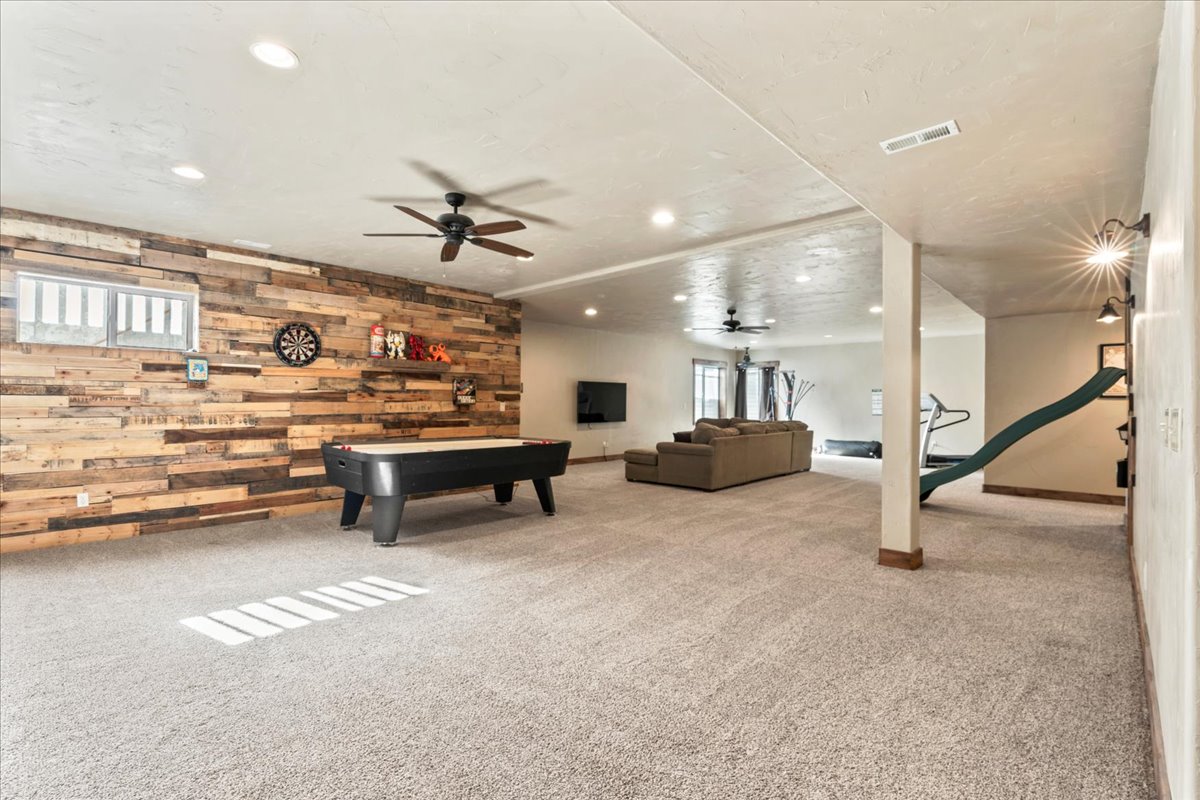 Rec room featuring wood walls, plenty of natural light, light carpet, recessed lighting, and ceiling fan