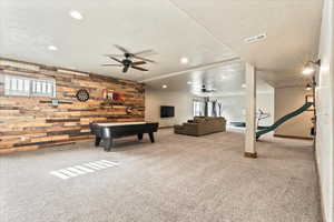 Rec room featuring wood walls, plenty of natural light, light carpet, recessed lighting, and ceiling fan