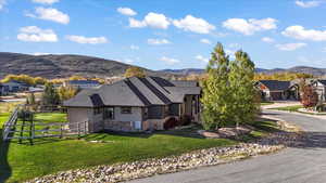 View of front of property with stone siding, a mountain view, stucco siding, and driveway