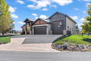 Craftsman-style house with a garage, concrete driveway, and stone siding