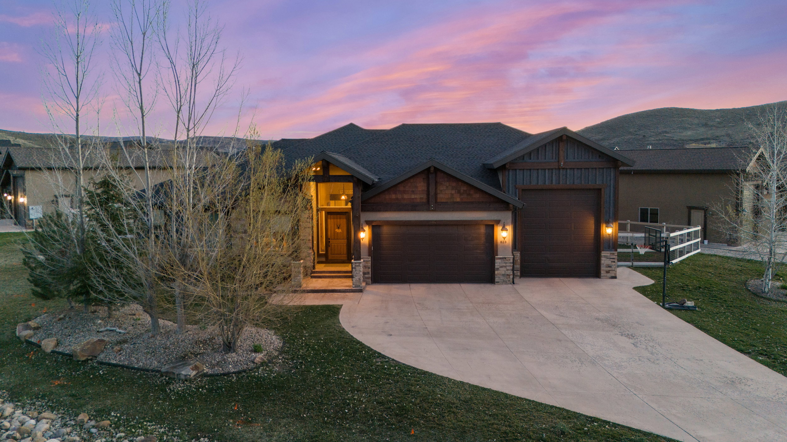Mountain Modern house with a garage, driveway, stone siding, and a front yard