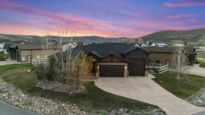 View of front of property with a garage, stone siding, a mountain view, and driveway