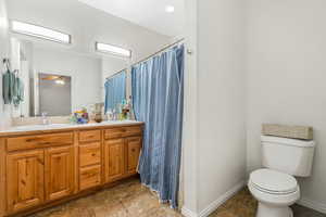 En suite bathroom with a shower, double vanity, ceiling fan, and tile patterned floors