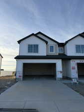 View of front facade featuring a garage, driveway, and board and batten siding