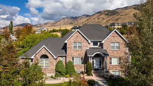 Traditional home featuring a mountain view, brick siding, and roof with shingles