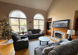 Living room with light wood-style flooring, a premium fireplace, and high vaulted ceiling