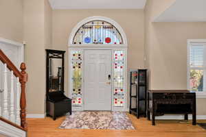 Entrance foyer with stairs, light wood-type flooring, plenty of natural light, and a towering ceiling