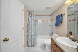 Bathroom with light tile patterned floors, a textured ceiling, vanity, and shower / bath combo