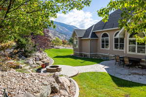View of green lawn with a patio, a mountain view, an outdoor fire pit, and a sunroom
