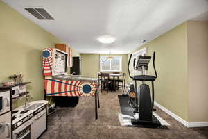 Exercise area featuring a textured ceiling and dark carpet
