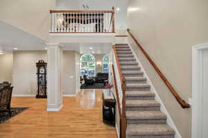 Entry and Stairs featuring decorative columns, a high ceiling, wood finished floors, and recessed lighting