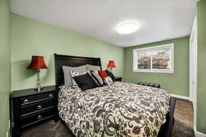 Bedroom with dark colored carpet and a textured ceiling