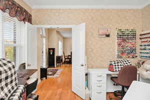 Office space featuring ornamental molding, light wood-style flooring, and wallpapered walls