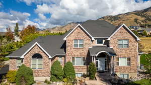 Traditional 2 story style home featuring brick exterior, a mountain view, and a shingled roof