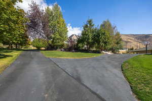 View of asphalt driveway to guest parking and to 4 car garage