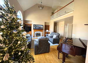 Living area featuring a fireplace, light wood-type flooring, and high vaulted ceiling